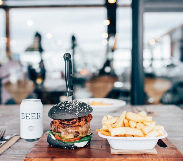 A burger, chips and beer sitting on a table in Ten27 Christchurch cafe.