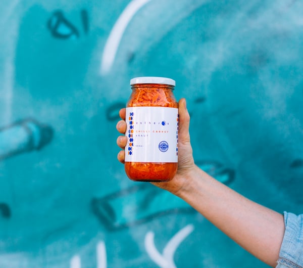 Jar of pickle against a blue wall.
