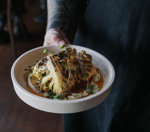 Waiter at Cucina holding a cauliflower dish.