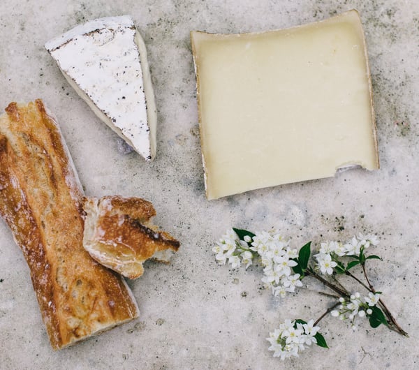 Cheese and bread on a table with flowers.