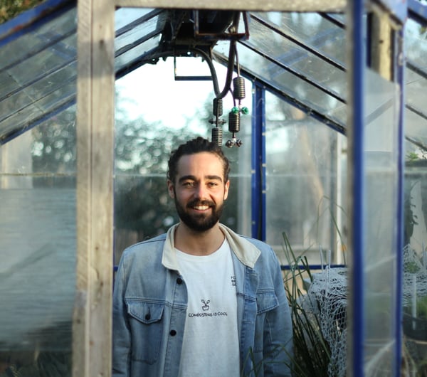 Jayden Kilnac looking to camera outside a glass house.