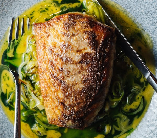 Close up of a seared fillet of fish in a shallow bowl of sauce at 5th Street restaurant Christchurch.
