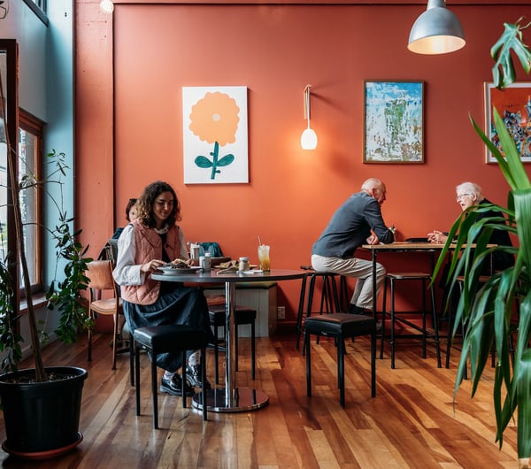 Customers sitting at low and high tables inside the cafe.