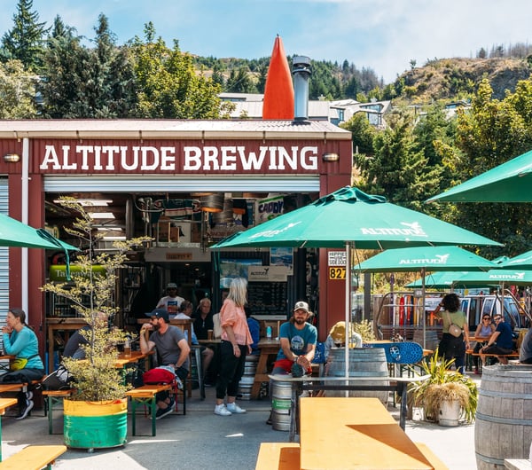 The colourful exterior of Altitude Brewing surrounded by large green umbrellas.