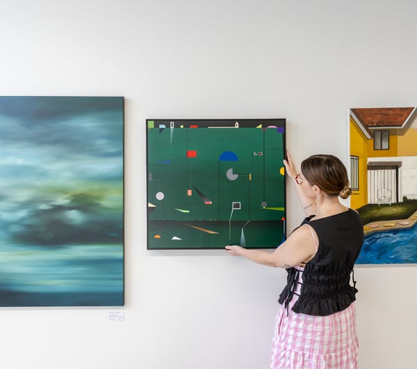 Gallery owner hangs a piece of art on the walls at Ashe.