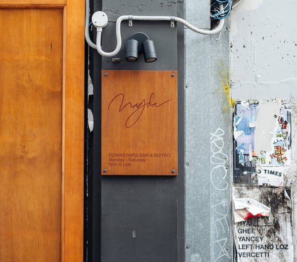A wooden sign with information on Bar Magda.