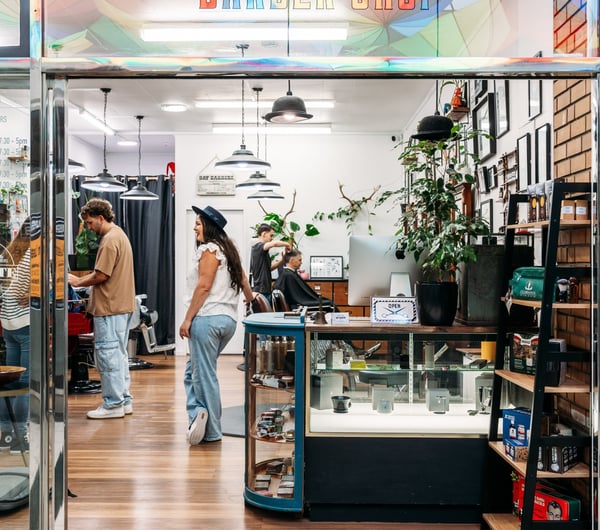 Customers and staff member sitting and standing inside Bays Barber in Tauranga.