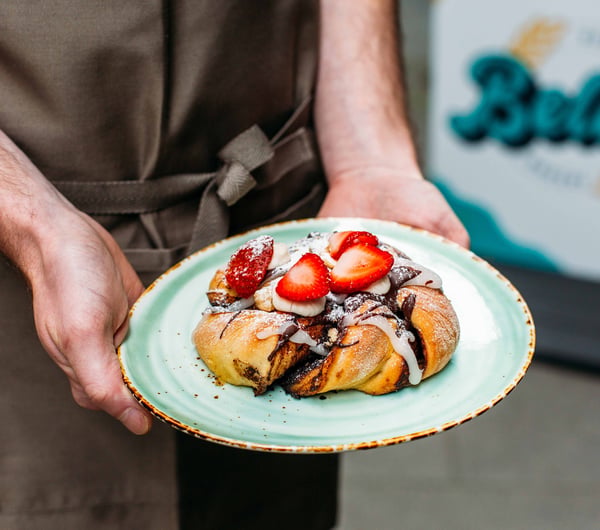 Person holding a vegan pastry with strawberries at Belén, Wellington.