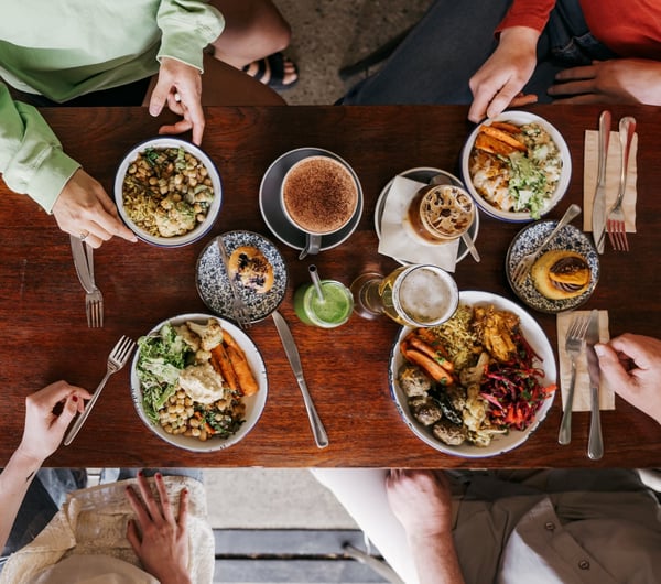 A flatlay of plates on a table with four people gathered around at Big Fig in Wānaka.