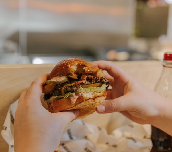 Close up of someone holding their burger about to take a bite.