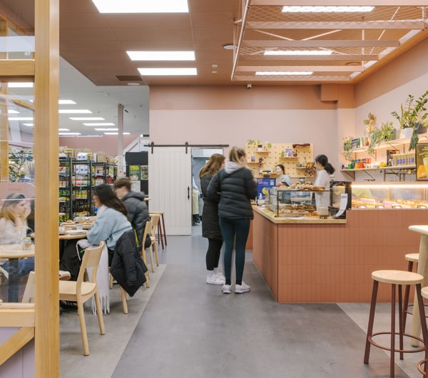 Customers sitting at tables, customers lining up to order at the counter at Blue Moon Bakehouse.