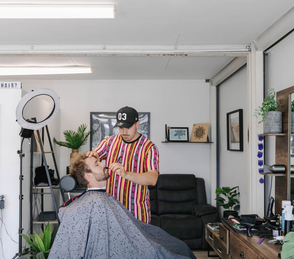 Man in the barbers seat getting a beard trim.