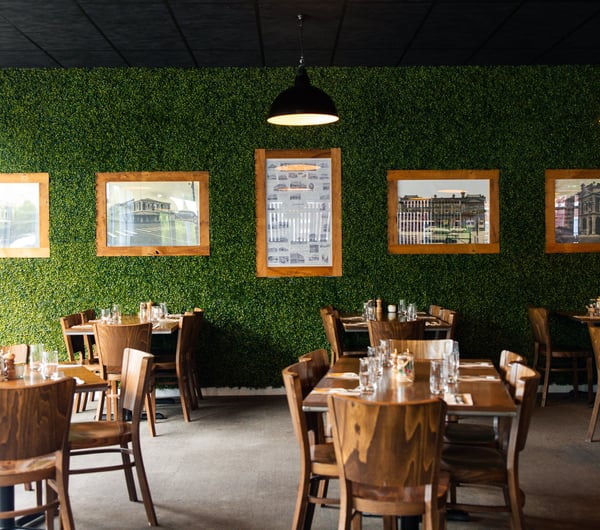 A fake green wall inside a large restaurant.