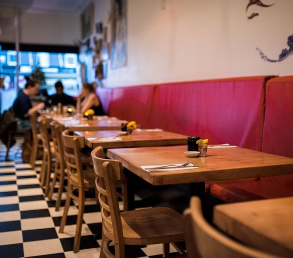 Wooden tables and chairs with red booth seating.