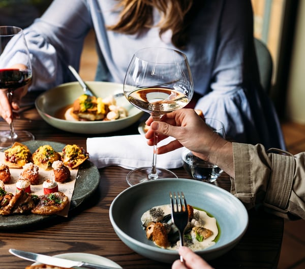 A man and woman sitting at table with beautiful plates of food.