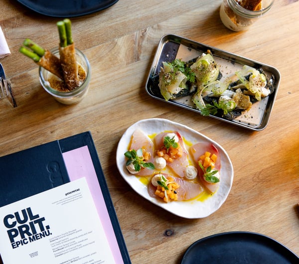 Plates of food next to a menu that sees 'Culprit' in black and white.