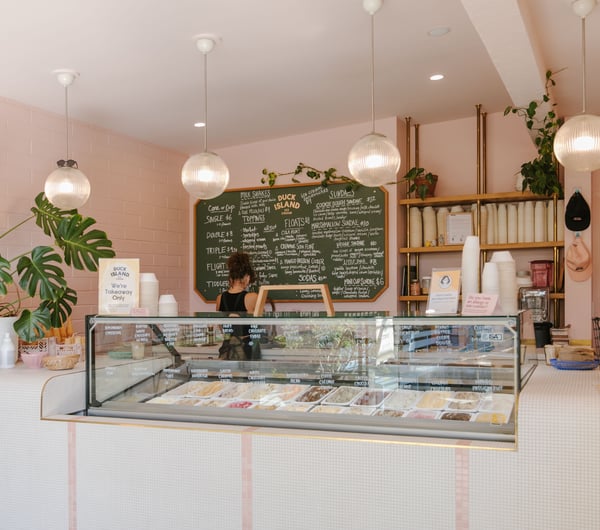 A staff member working behind a counter at a brightly decorated ice cream shop.
