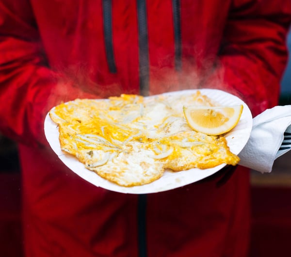 A giant whitebait pattie with a lemon wedge on the side.