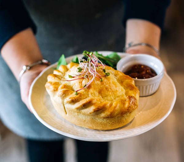 Close up of a waitress holding a pie.
