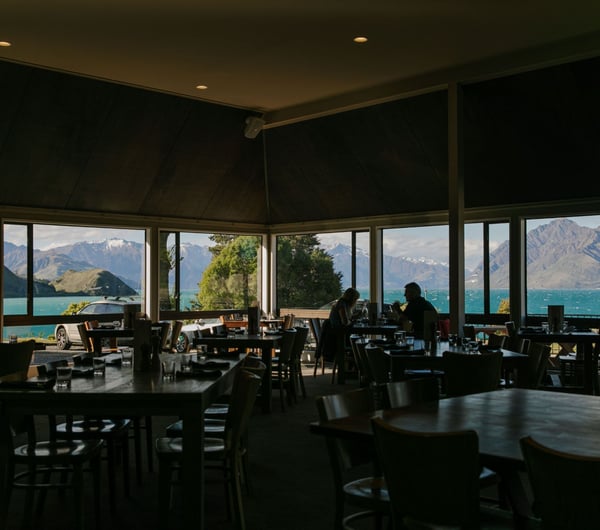 Inside the restaurant where people are dining and looking out the windows over the lake.