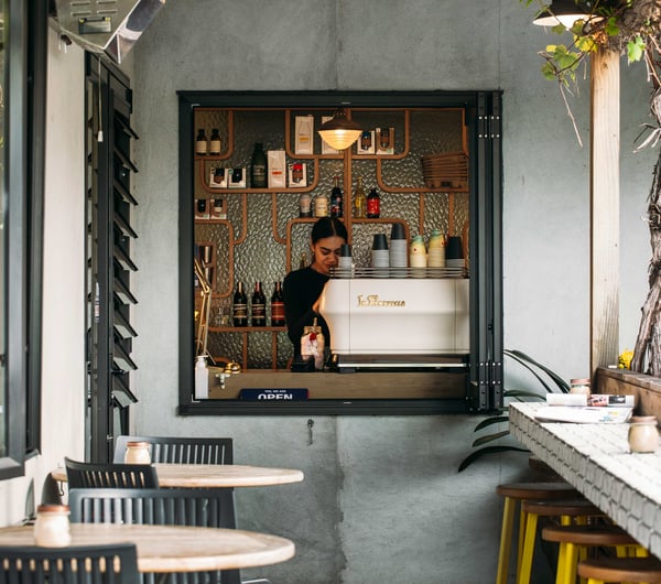 A barista working behind a small hole-in-the-wall window.