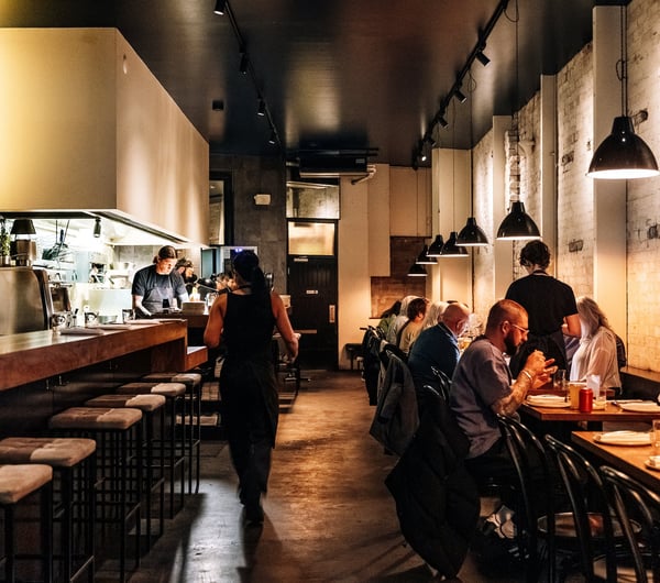 Long narrow restaurant with people dining in rows.