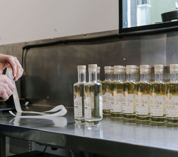 Bottles of gin lined up in a row waiting for stickers to be placed on them at Humdinger Gin Distillery in Geraldine.