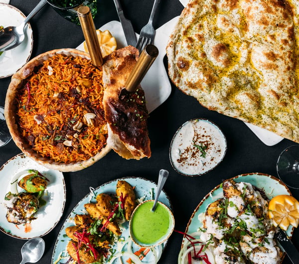 A flatlay of curries and naan on plates.