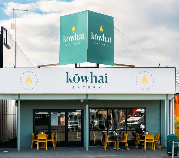 Cafe building exterior with bright green signage for Kōwhai Eatery.