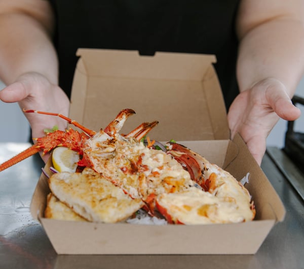 Takeaway box with cooked crayfish dish inside.