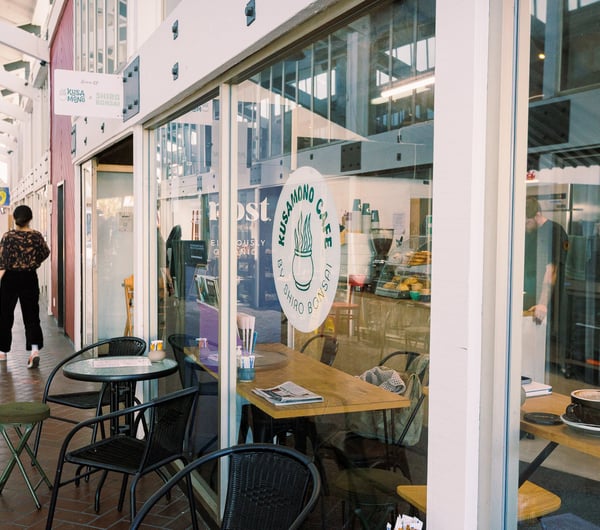 Customer walking out the front door of Kusamono Cafe into the laneway and tables are outside the cafe entrance.
