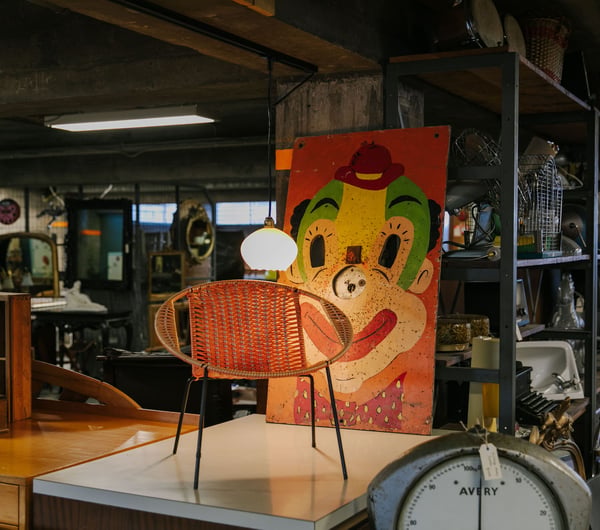 Vintage chair with retro painting of clown's face behind it at La Voute, Christchurch.