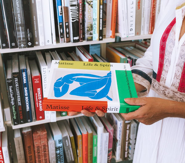 Woman holding a book about artist, Matisse, at Lamplight Books, Auckland.