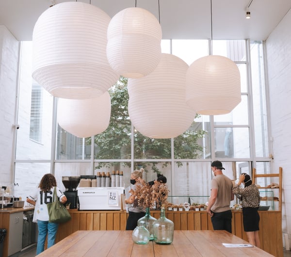 Large wooden tables with pendant paper lanterns above at Little Rosie, Auckland.
