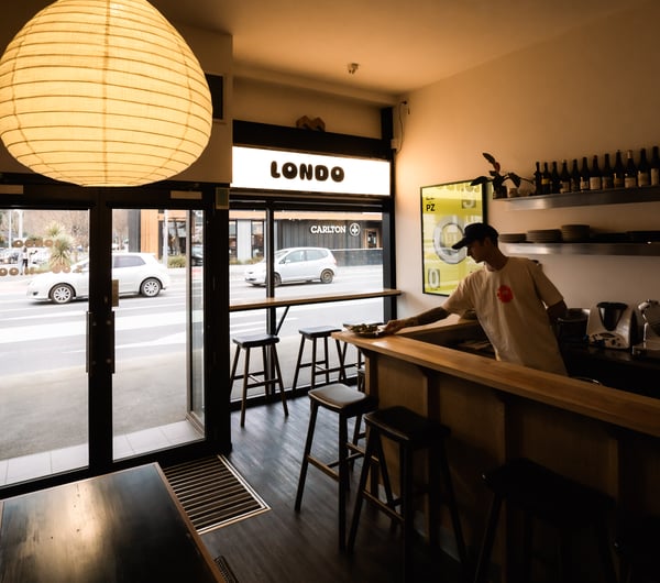 A man placing a plate of food on the counter at Londo in Christchurch.