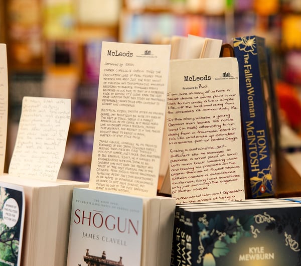 Close up of handwritten reviews on paper slips sticking out from books.