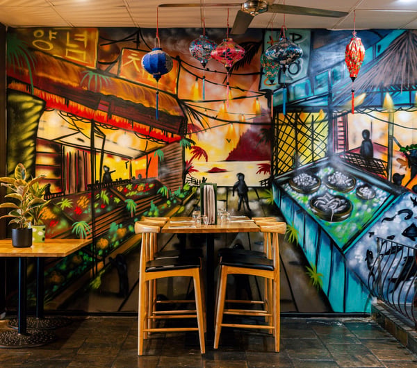 Colourful mural on the wall behind a table and chairs in the dining room of Mekong Buffalo.
