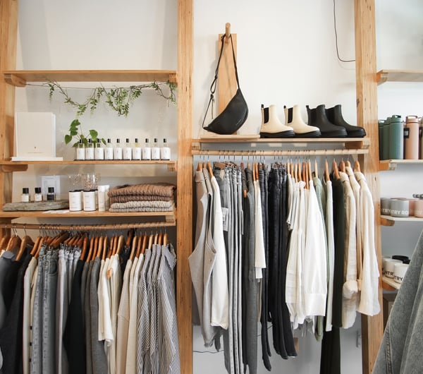Clothes, shoes and bottles hung on wooden display racks and shelves.