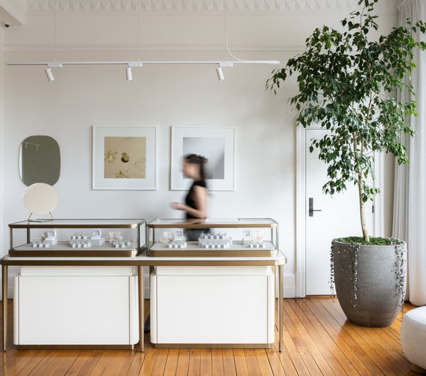 Wide shot of jewellery showroom with cabinet full of jewellery and a shop assistant behind at Naveya & Sloane Jewellery.