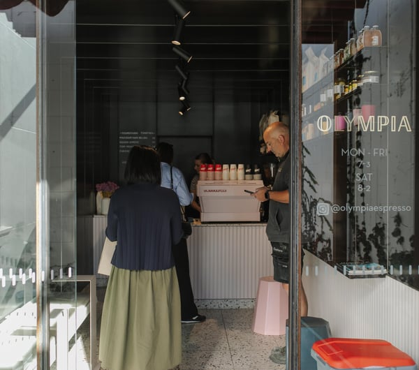 People lining up inside a small cafe.