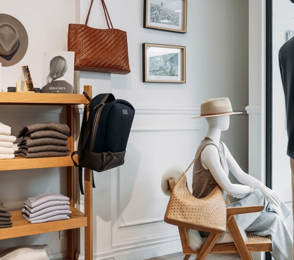 Folded knitwear on wooden shelves and mannequins accessorised with hats and woven shoulder bags.