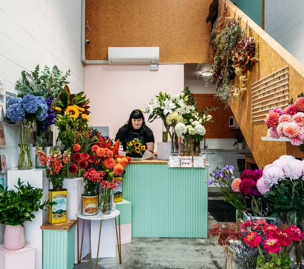 A woman behind a counter at a flower shop.