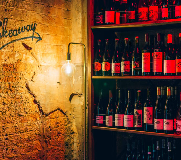 Shelves of wine with a takeaway sign.