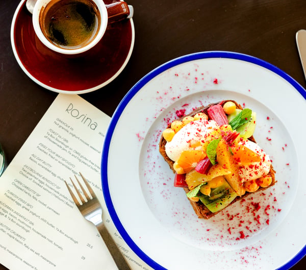 Plate of bright milk toast next to a long black coffee on cafe table