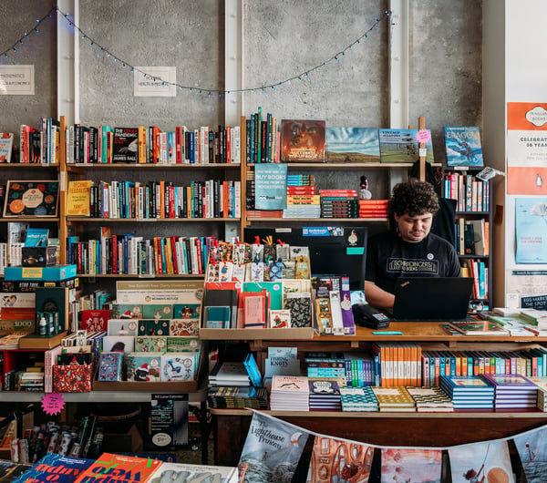 Male worker behind the counter of an independent bookstore in Petone Lower Hutt