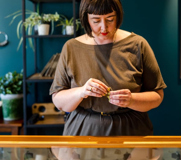 A close up of a woman wearing a blunt hair cut holding a ring.