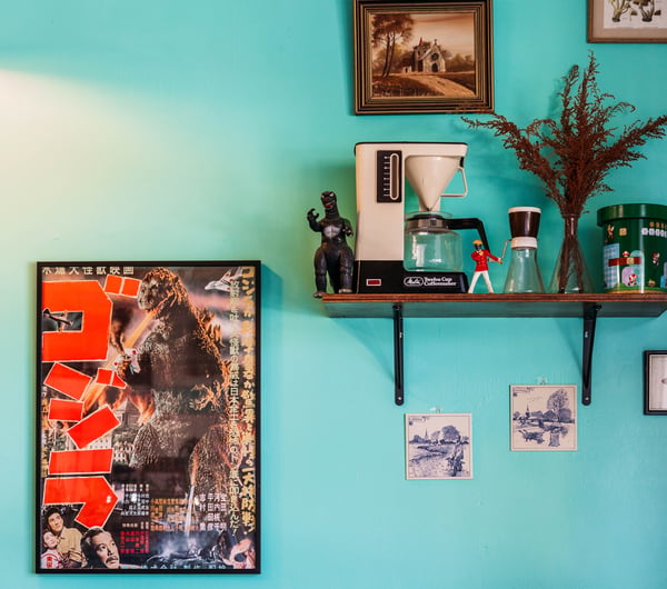 Wall art and curiosities on the shelf on the bright blue wall at Space Cadet, Hamilton.
