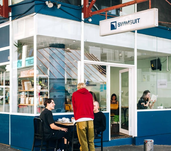 Exterior blue cafe with patrons eating outside.