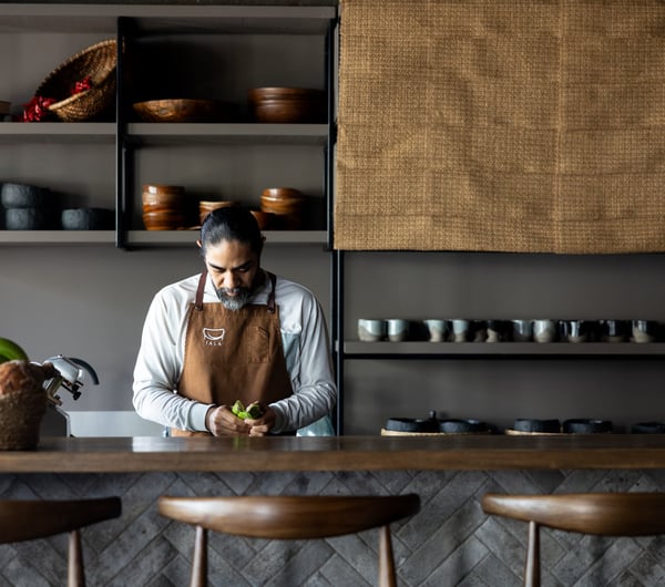 A male chef working behind the counter inside an open kitchen.