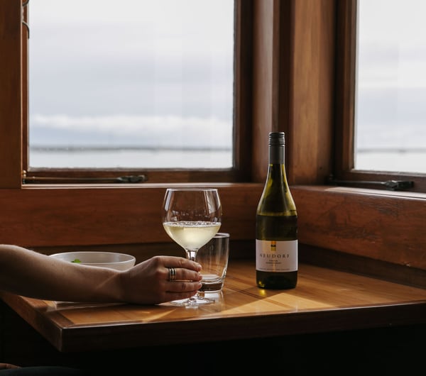 Woman holding a glass of white wine at Boat Shed Cafe.